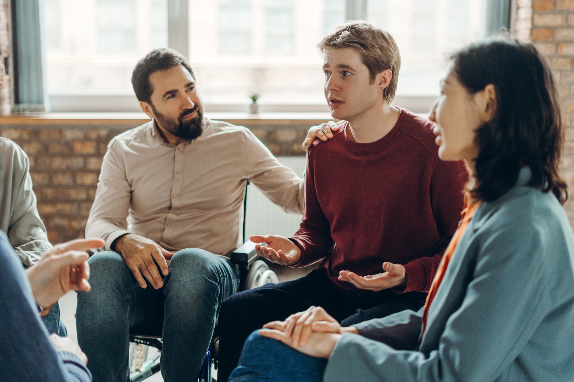 Diverse group of multinational people supporting each other during group therapy session
